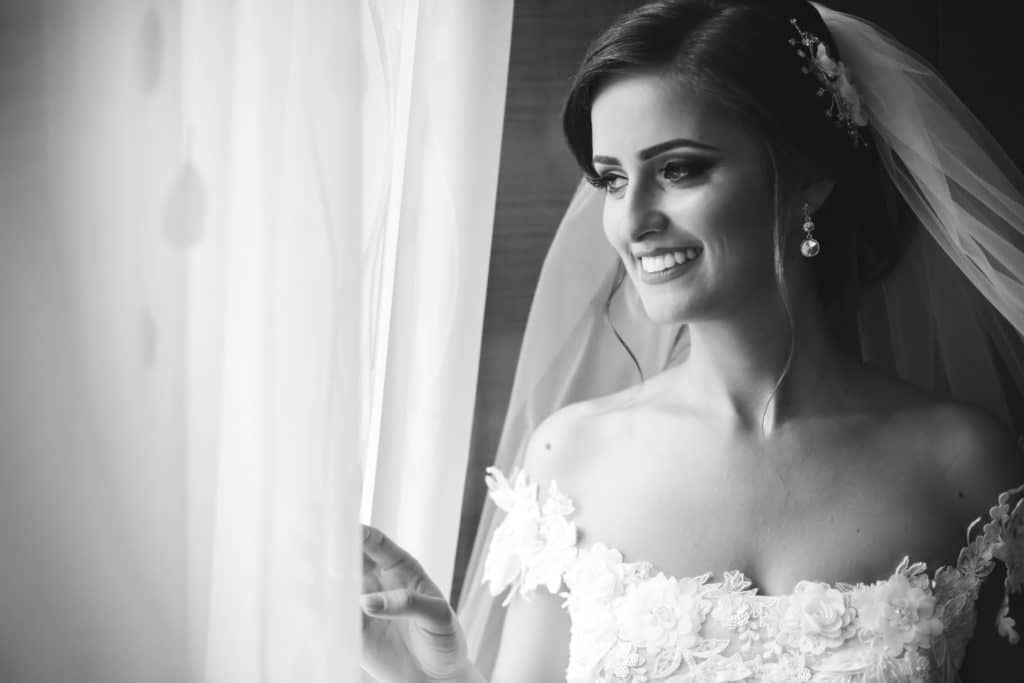 Bride with off shoulder neckline smiling by window