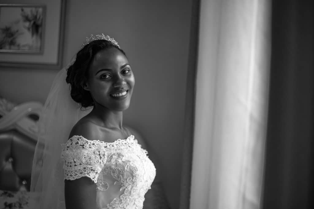 Bride with off shoulder neckline smiling by window