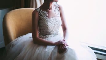 Bride with square wedding dress neckline smiling by window